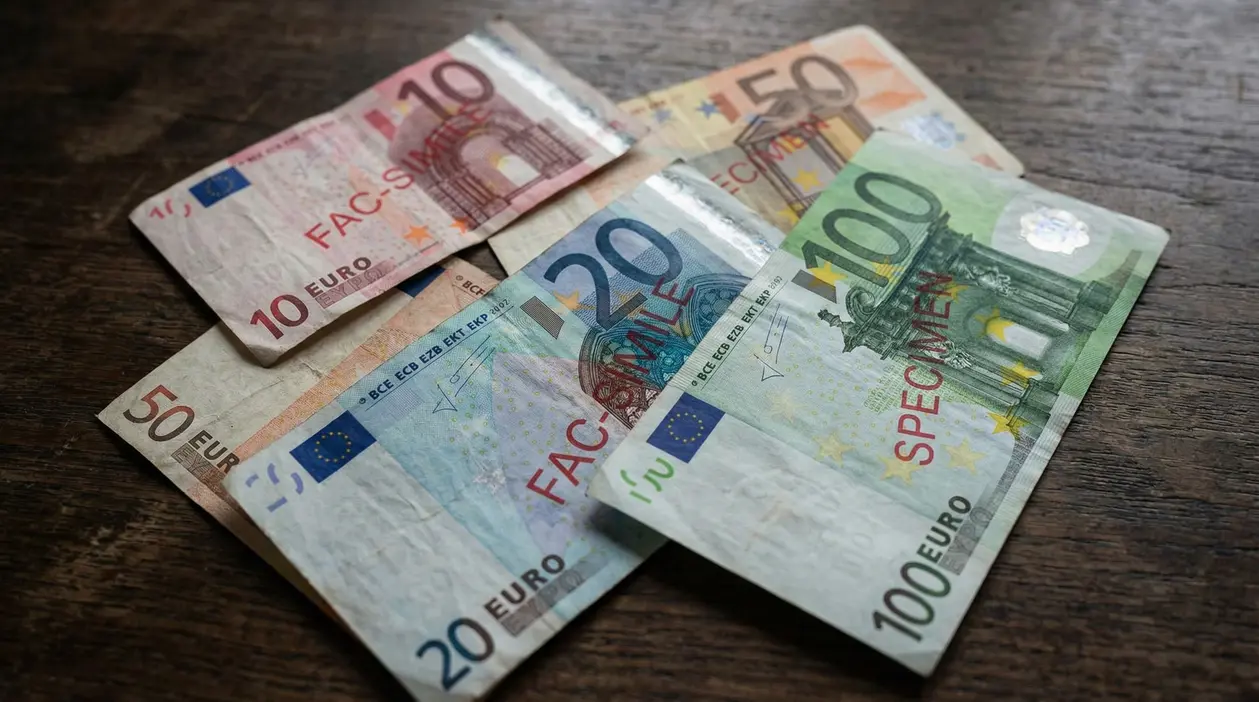 Banconote in euro disposte su un tavolo di legno, alcune marcate come fac-simile o specimen