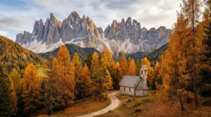Cappella circondata da alberi autunnali ai piedi delle Dolomiti in Trentino