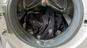 Asciugamani bagnati con residui di detersivo all'interno di una lavatrice aperta